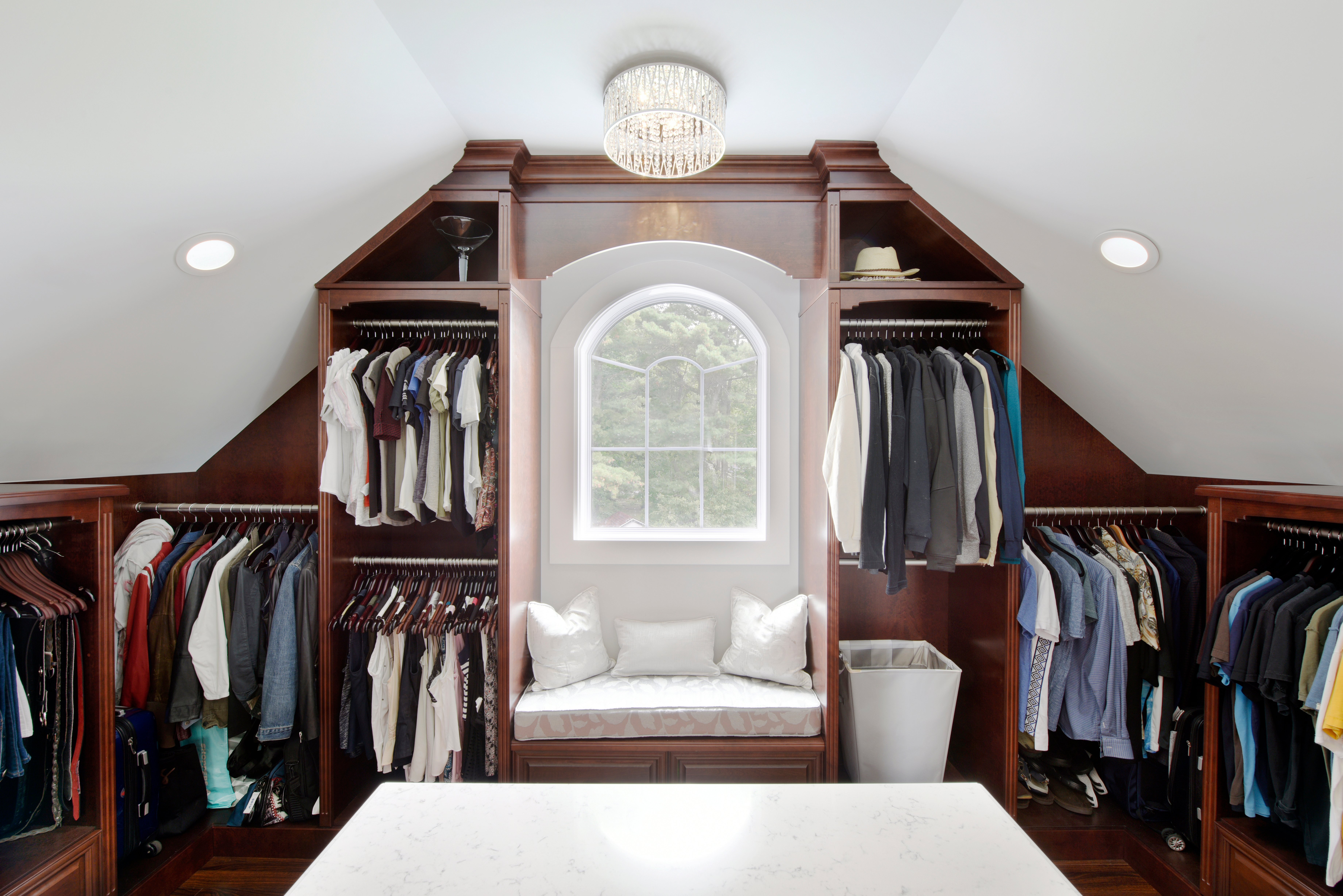 A stunning custom closet with a window and crystal chandelier.