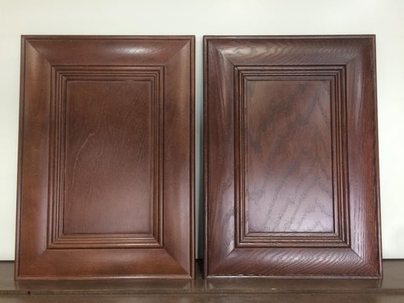 A stained oak and birch cabinet door side by side.