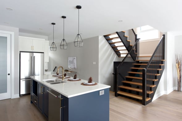 A blue and white kitchen with wooden stairs.