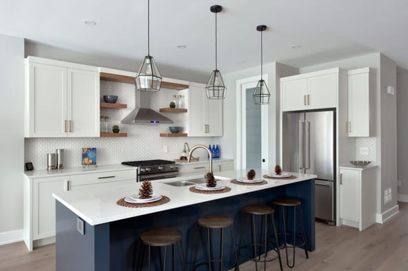 A blue and white kitchen with wooden stools and floating shelves.