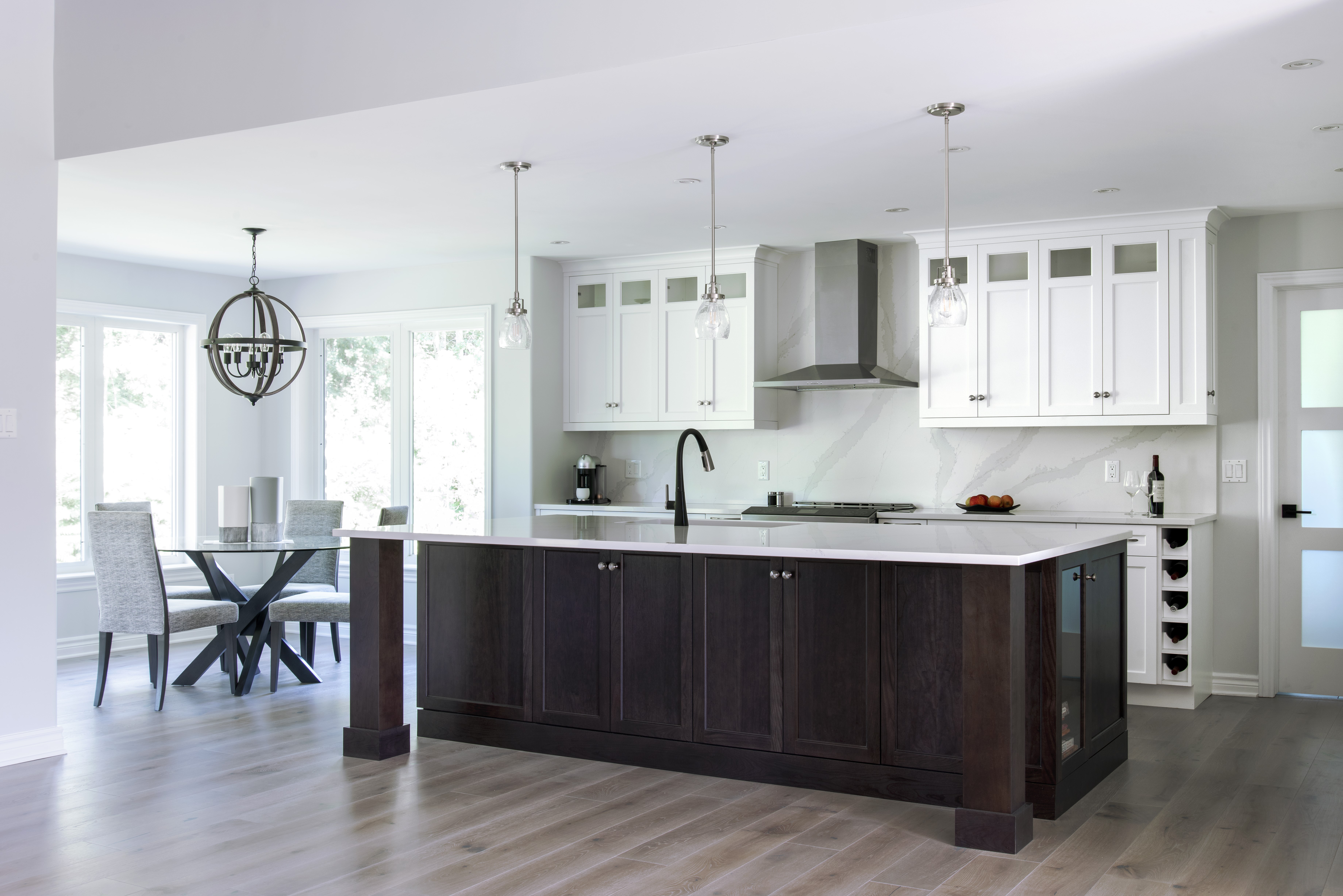 A dark cherry island surrounded by white perimeter cabinets.