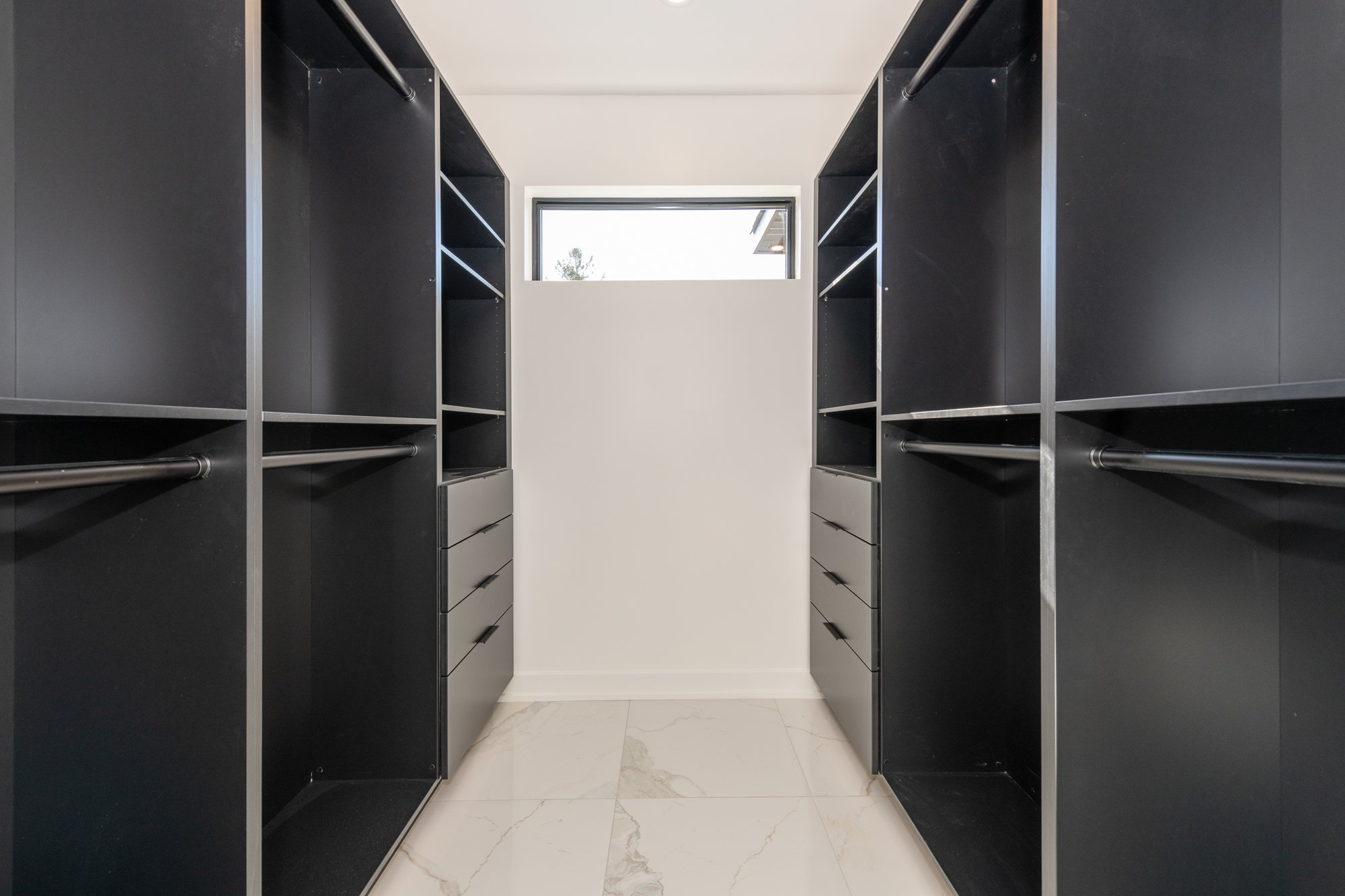 A master closet featuring black Deslaurier custom cabinets.