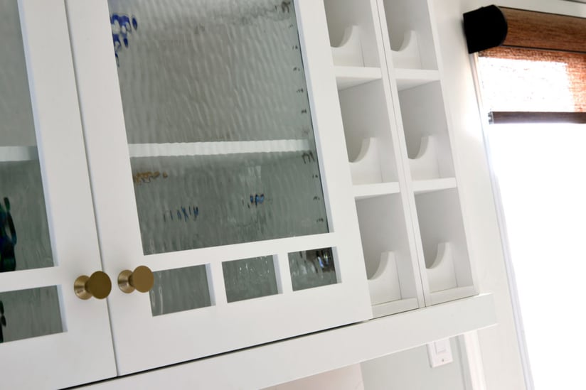 A kitchen with architectural mullion glass upper cabinets