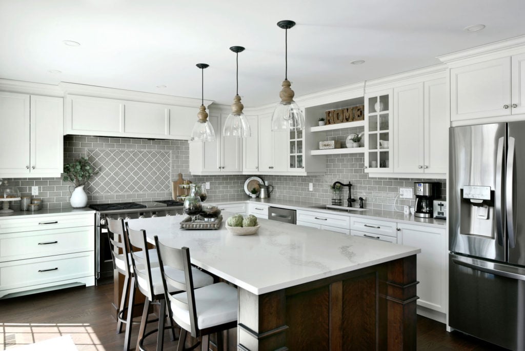 A custom kitchen with white cabinets and a grey tiled backsplash.