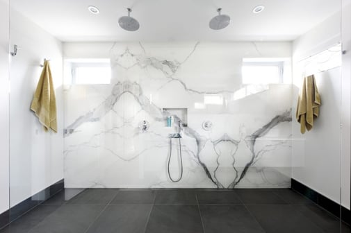 A modern spacious bathroom featuring a marbled wall.