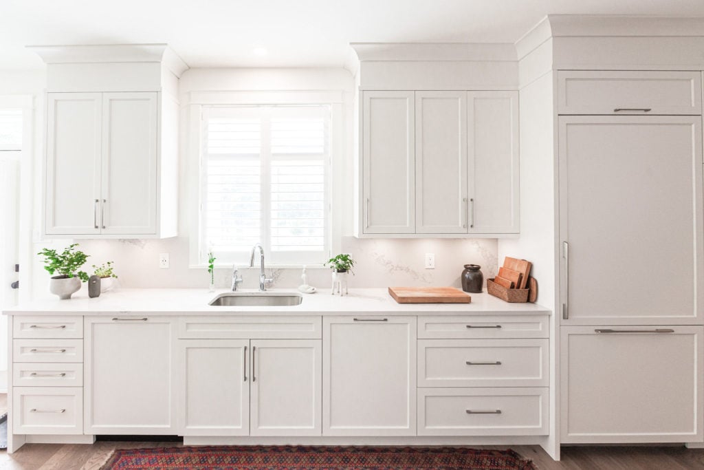 A kitchen that extends cabinets to ceiling height with bulkhead trim and crown moulding.