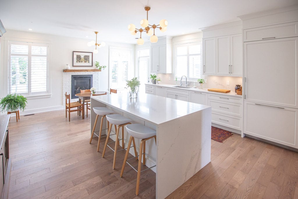 A stunning white kitchen design boasting a centrepiece waterfall quartz countertop.