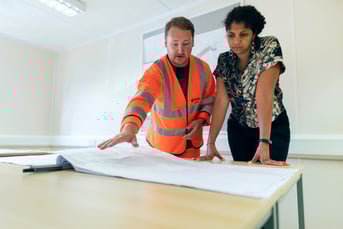 A contractor presenting a floor plan to a homeowner.